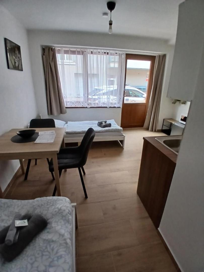 Postele, stůl a okno do ulice
